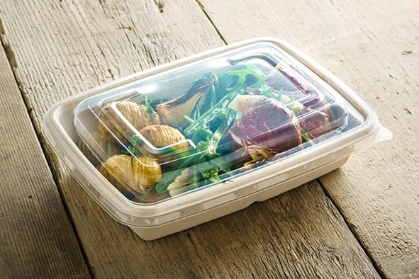 Bagasse container full of food on a wooden table